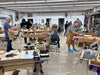 Woodworking class in progress with students and instructors in a workshop.