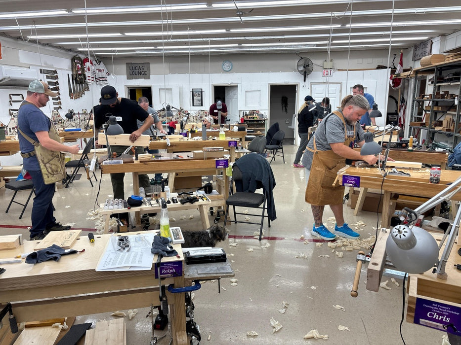 Woodworking class in progress with students and instructors in a workshop.