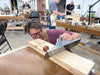 Person working with a tool on a wooden block in a workshop setting