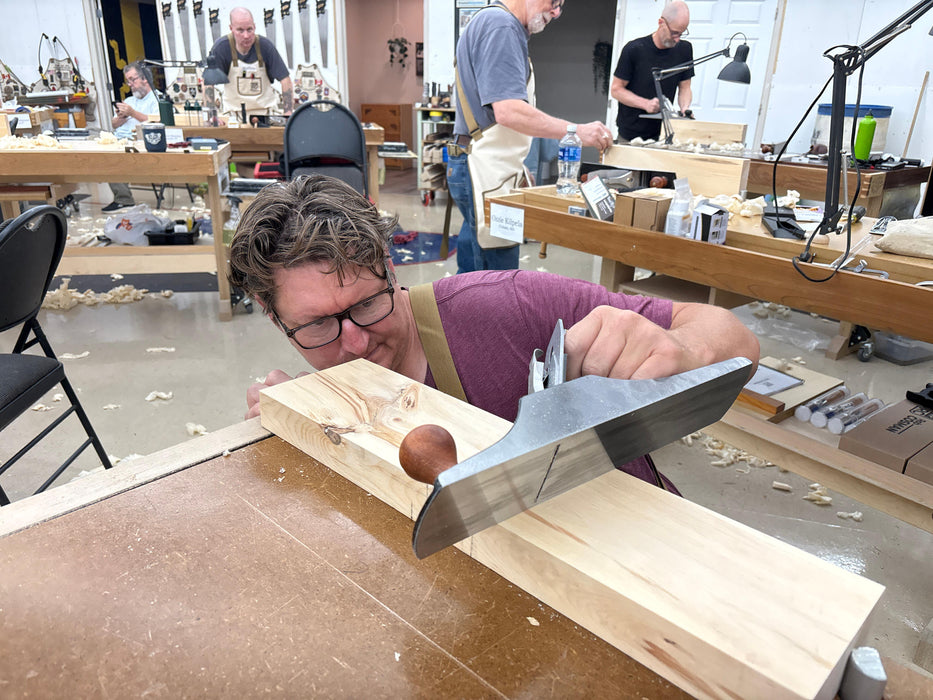 Person working with a tool on a wooden block in a workshop setting