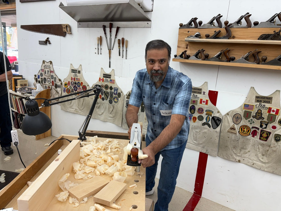 Man working with wood in a workshop with aprons and tools in the background