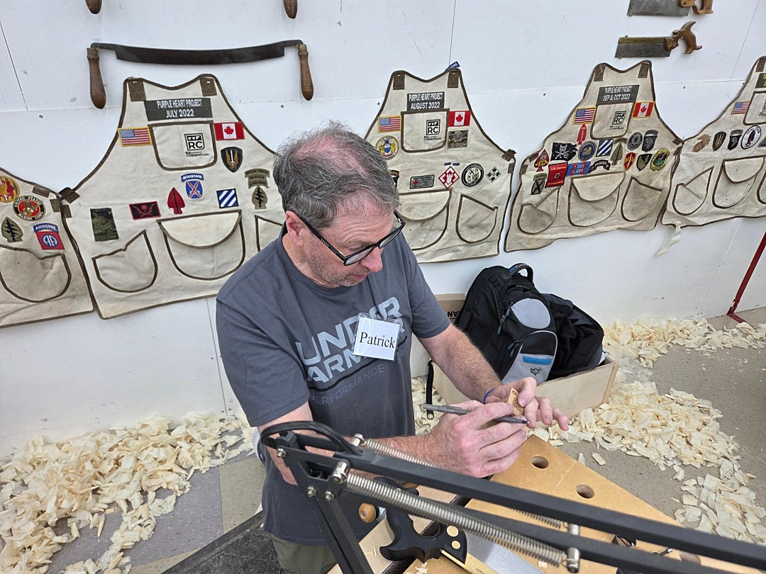 Man working on a craft project with leather aprons in the background