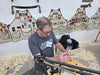 Man working on a craft project with leather aprons in the background
