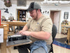 Man working on a project in a workshop with tools and equipment around.