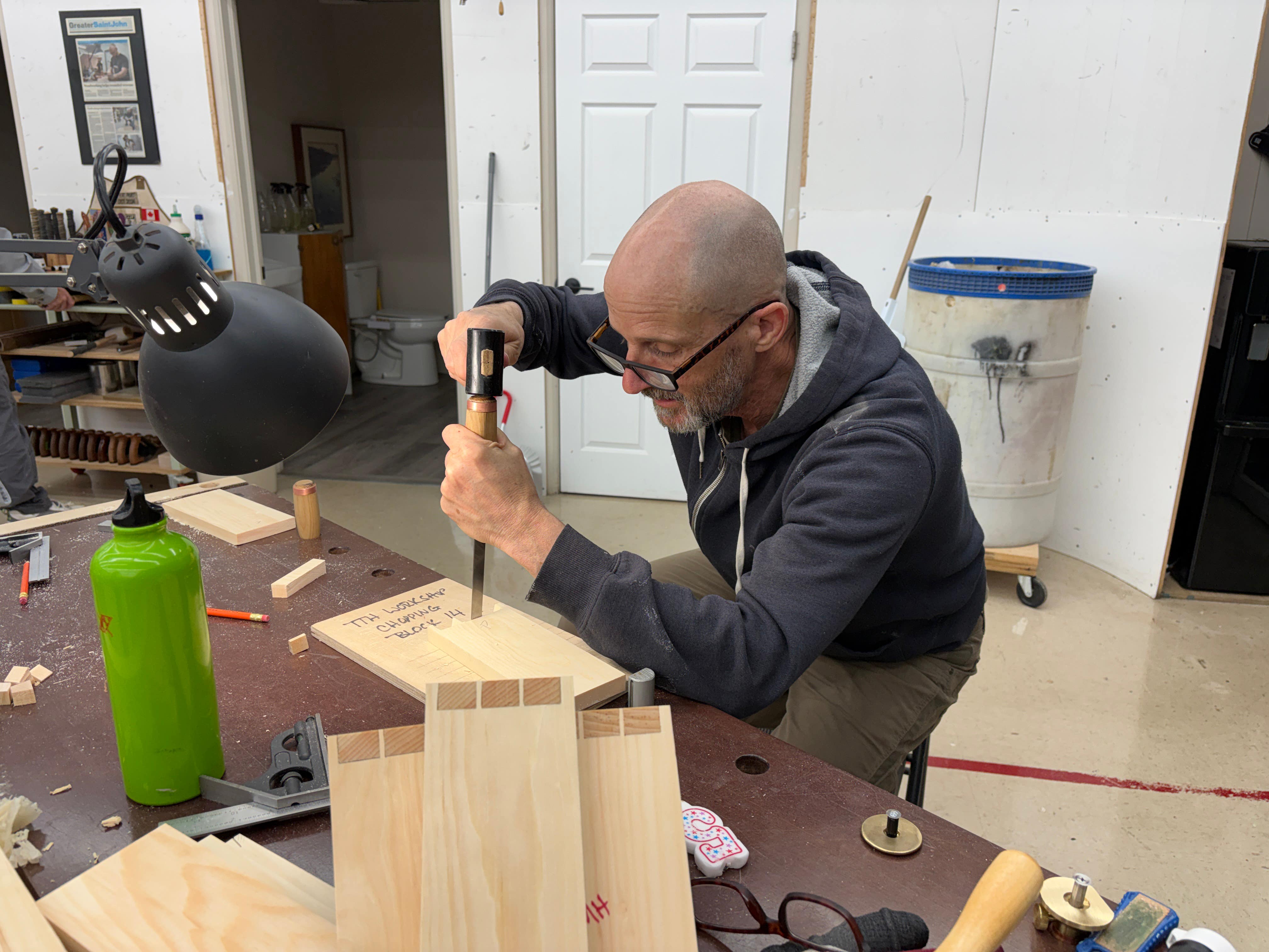 Man working on a wooden project with tools in a workshop setting