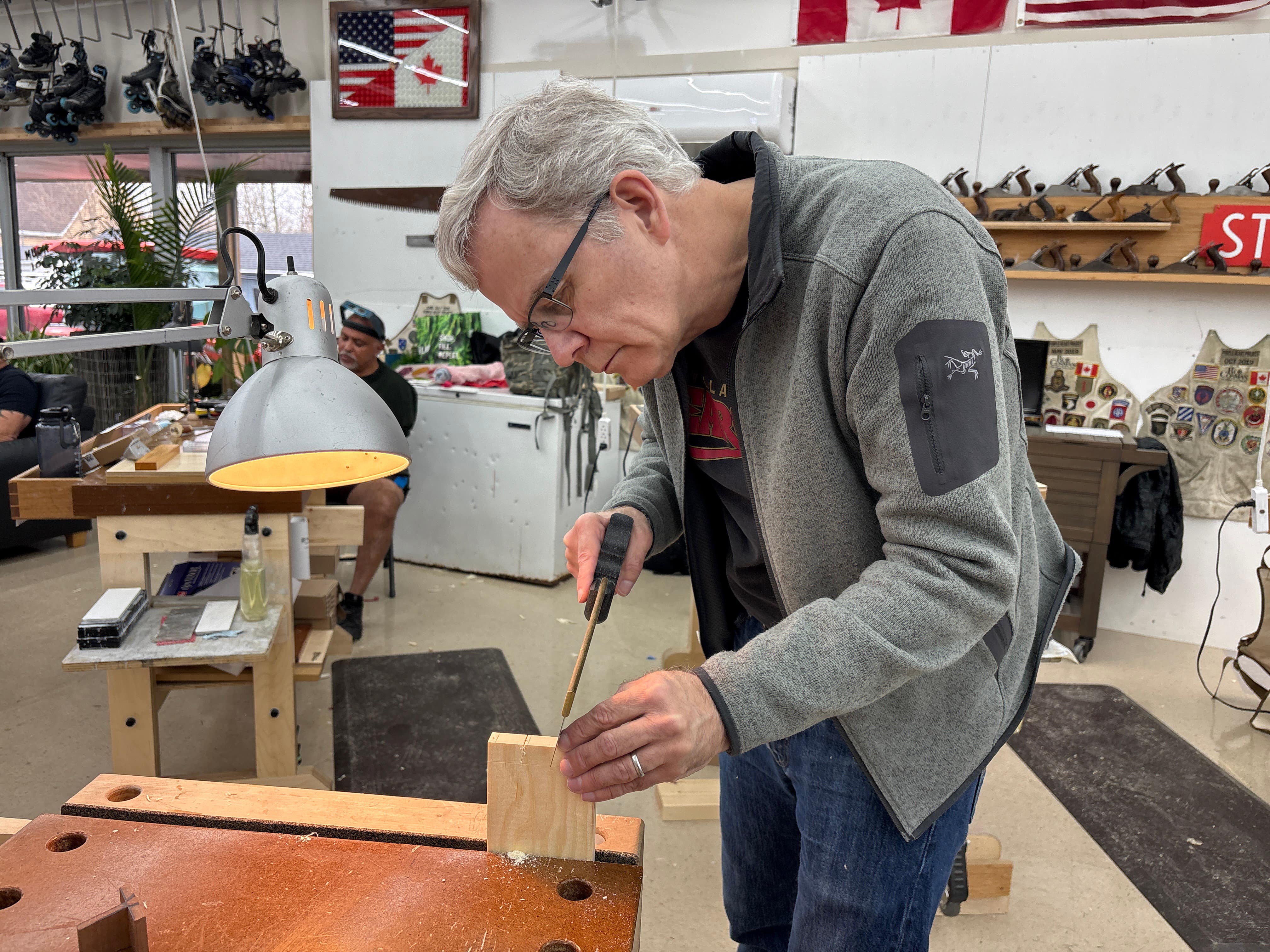 Man measuring wood in a workshop with tools and equipment around