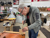 Man measuring wood in a workshop with tools and equipment around