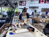 Person working on a woodworking project in a workshop with tools and materials around.