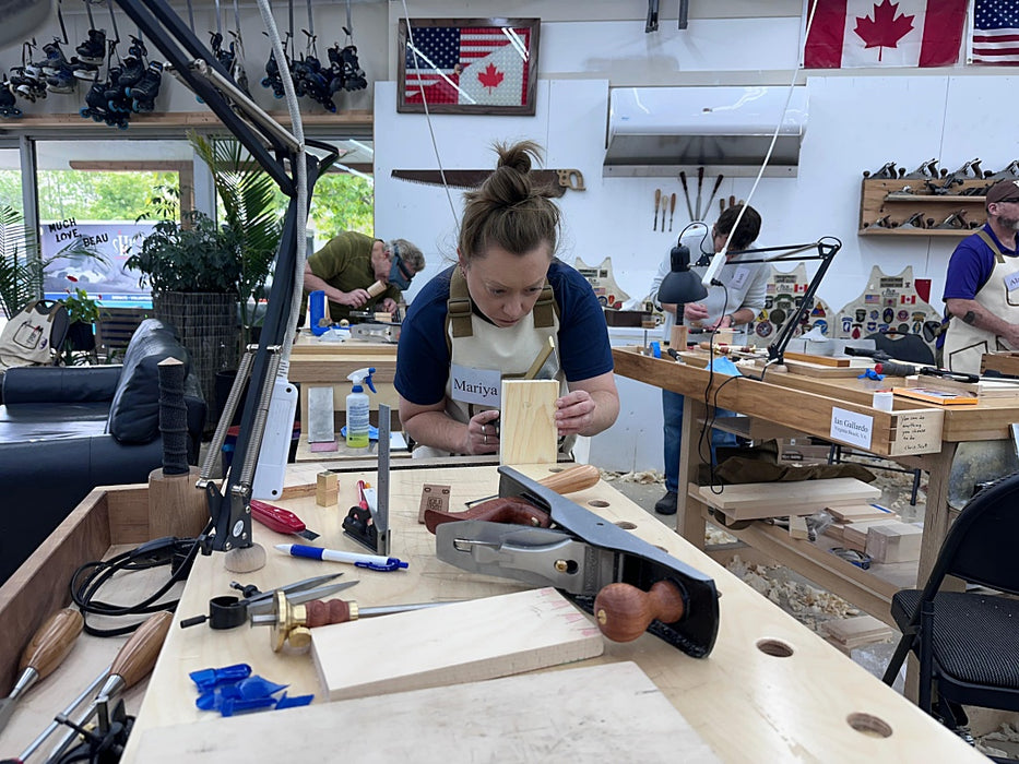 Person working on a woodworking project in a workshop with tools and materials around.