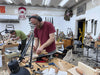 Man working in a workshop with tools and materials around him.