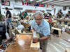 Man working on a project in a workshop with various tools and equipment around.