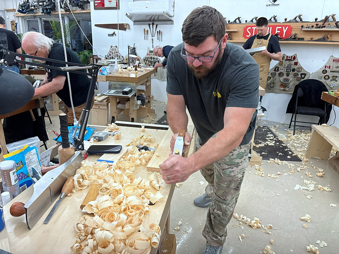 Man working with wood shavings in a workshop setting
