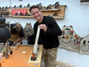 Man in workshop holding a piece of wood, with tools and Stanley branding in the background.