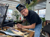 Man working on a project in a workshop with tools and materials around him.