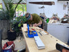 Person working at a wooden workbench with tools and materials in an outdoor setting