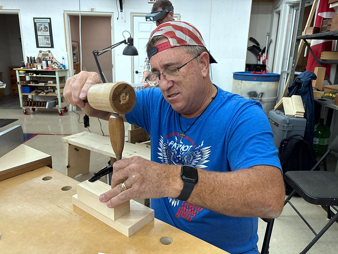 Man working with a wooden tool in a workshop setting
