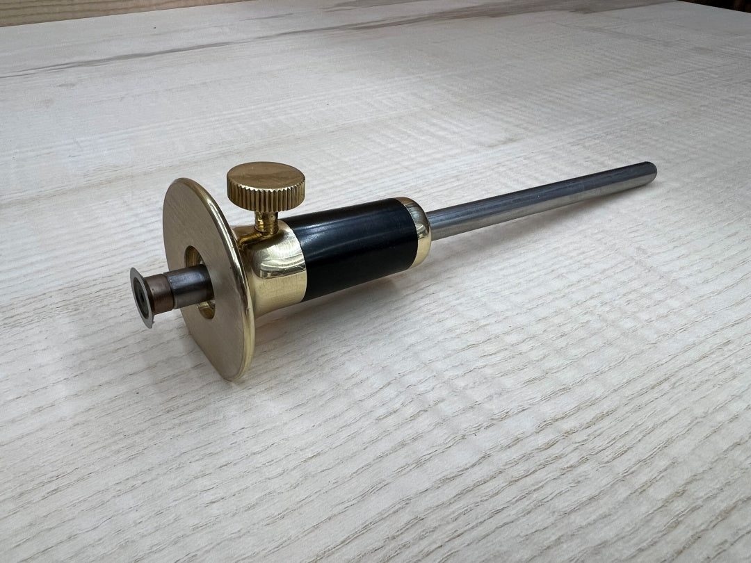Mechanical tool with brass and black components on a light wooden surface