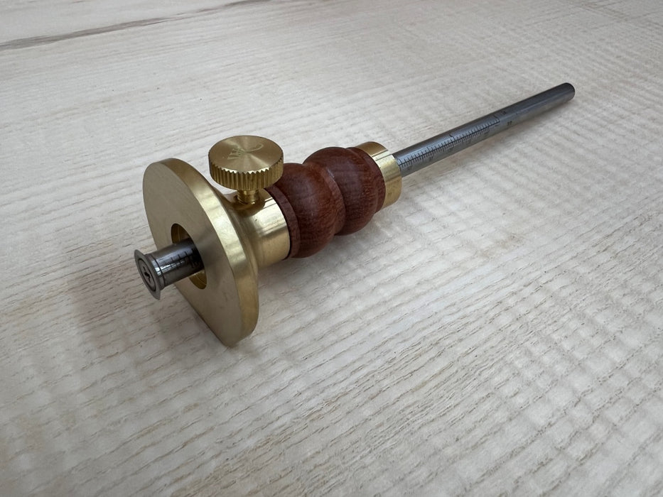 Tool with brass and wooden components on a light wood surface