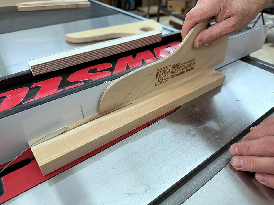 Wooden push stick being used on a table saw with a visible brand logo.