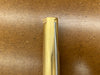 A close-up of a Rob Cosman 1-inch brass bench dog resting on a brown textured surface.