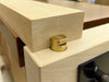 Close-up of a lRob Cosman 1-inch brass bench dog holding a piece of wood with its primary face.