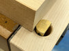 A close-up of a Rob Cosman 1-inch brass bench dog holding a piece of wood with its secondary faced