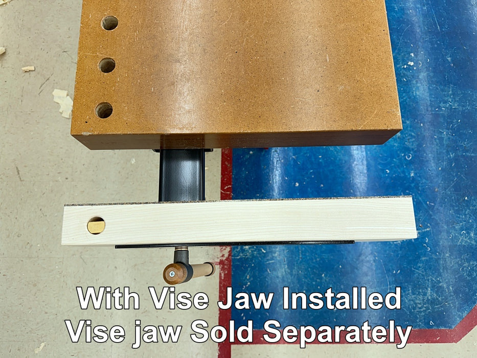 A close-up of a woodworking vise setup showing a brown wood block with pre-drilled holes, a black vertical column, and a white guide rail with a brass bolt. White text at the bottom reads 'With Vise Jaw Installed Vise jaw Sold Separately' on a workshop floor background.