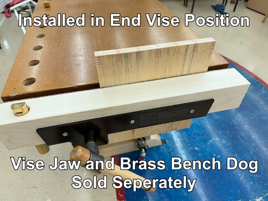 A woodworking vise setup with overlaid text reading 'Installed in End Vise Position' and 'Vise Jaw and Brass Bench Dog Sold Separately.' The photo shows a light wood bench dog attached to a workbench end, with a wood block positioned above it on a workshop floor.