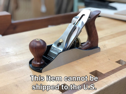 Wooden plane tool on a wooden surface with text indicating it cannot be shipped to the U.S.